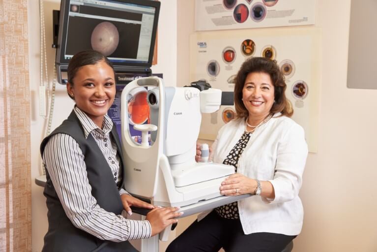 Dr Tereza Fawzy and a patient, sitting, smiling next to medical equipment.